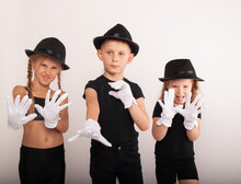 Boys And Teenage Girl In The Image Of A Mime With A White Mask On Her Face Isolated On A White Background In White Theater Gloves, Theater Children Actors, Actress.