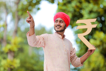 Sticker - Young indian farmer holding rupees symbol in hand.