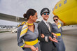Aviator and two joyous flight attendants by a landed aircraft