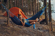 Camper chilling in her blue hammock near tent