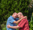 © Robert - An elderly gay male married couple in love, embrace outdoors.