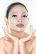 A beautiful Asian woman wearing a collagen face mask. Skincare concept, anti-aging moisturizing mask, hydrogel face mask, cosmetology.