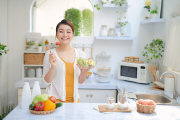 Wall Mural - Pretty woman eating a salad in the kitchen