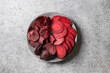 Vegetable beetroot dry and fresh chips in plate on a gray background. Top view. Healthy vegan snack.