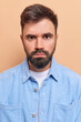 © wayhome.studio  - Vertical shot of handsome bearded man looks seriously has strict expression gazes directly at camera wears blue velvet shirt smirks face isolated over beige background. Human face expressions