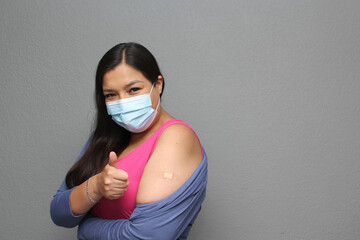 Latino adult woman shows her arm that just received the Covid-19 vaccine in the new normal for the pandemic
