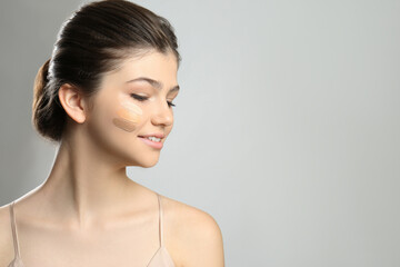 Wall Mural - Beautiful girl on light grey background. Using concealers and foundation for face contouring