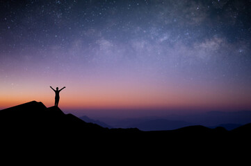 Wall Mural - Silhouette of young female traveler and backpacker watched the star and milky way alone on top of the mountain before sunrise. She enjoyed traveling and was successful when he reached the summit.