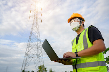 Sticker - Asian male electrical engineer stands holding a laptop computer at a power plant running and plots to inspect high-voltage poles at a power station.