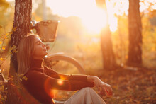 Happy Active Young Woman Sitting Near Vintage Bicycle Bike In Autumn Park At Sunset. European Female Enjoying Good Autumn Weather And Sunlight.