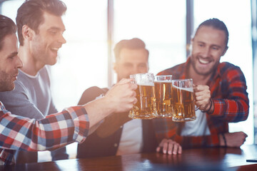 Canvas Print - Happy young men in casual clothing toasting each other with beer and smiling