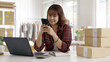 © ChayTee - Young asia seller woman happy work on laptop busy cellphone call chat to customer at home office desk use digital tablet computer in SME online store social e-commerce sale page service web support.