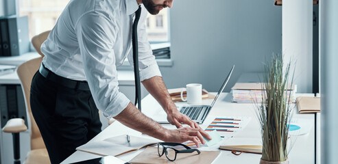 Canvas Print - Confident young man in shirt and tie working with documents in office