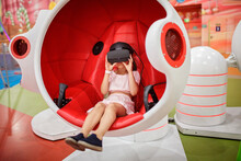 Young Girl Wearing Virtual Reality Googles And Experiencing Virtual Reality In Moving Interactive Chair At Amusement Park, Future Today, New Entertainment, Indoor Lifestyle