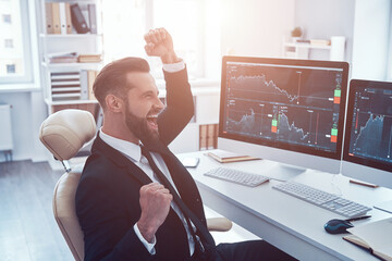 Canvas Print - Happy young man in shirt and tie cheering and gesturing while working in the office