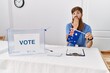 © Krakenimages.com - Caucasian man with long beard at political campaign election holding australia flag covering mouth with hand, shocked and afraid for mistake. surprised expression