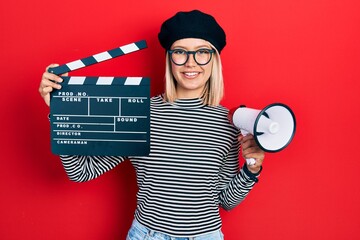 Canvas Print - Beautiful blonde woman holding video film clapboard and megaphone smiling with a happy and cool smile on face. showing teeth.