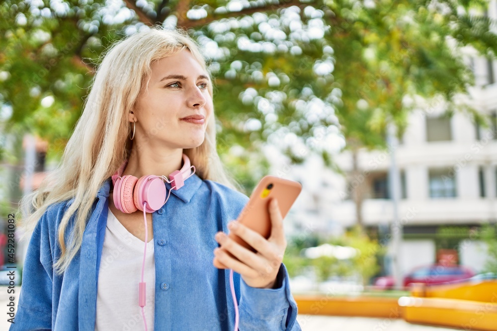 Young blonde woman outdoors on a sunny day using smartphone
