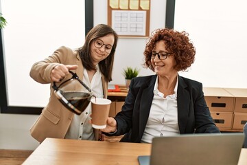 Wall Mural - Group of two women working at the office. Mature woman and down syndrome girl working at inclusive teamwork.