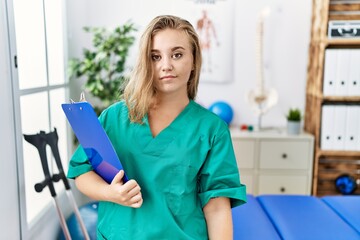 Wall Mural - Young caucasian woman working at pain recovery clinic relaxed with serious expression on face. simple and natural looking at the camera.