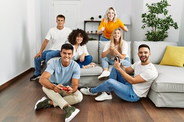 Wall Mural - Group of young friends smiling happy playing video game at home.