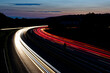 Lichtzieher von Fahrzeugen in einer langezogenen Kurve einer zweispurigen Straße
