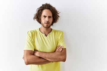 Poster - Young hispanic man standing over isolated background skeptic and nervous, disapproving expression on face with crossed arms. negative person.