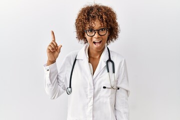 Wall Mural - Young african american woman wearing doctor uniform and stethoscope pointing finger up with successful idea. exited and happy. number one.