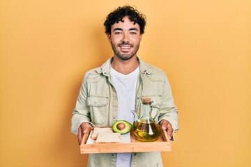 Canvas Print - Young hispanic man holding tray with breakfast food smiling with a happy and cool smile on face. showing teeth.