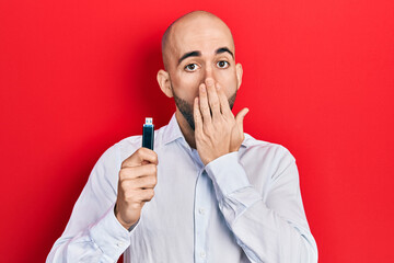 Sticker - Young bald man holding removable memory usb covering mouth with hand, shocked and afraid for mistake. surprised expression