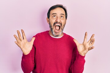 Poster - Middle age hispanic man wearing casual clothes crazy and mad shouting and yelling with aggressive expression and arms raised. frustration concept.