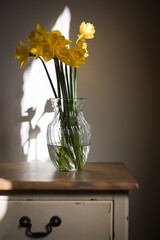 Wall Mural - Daffodils yellow flowers vase rustic timber table draw shadow light window moody dark 