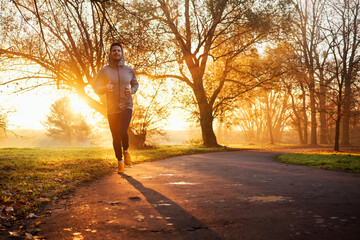 Wall Mural - Adult male running in park at autumn sunny morning