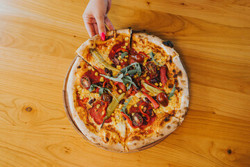 Wall Mural - A top view of a female picking up a pizza slicesfrom the table