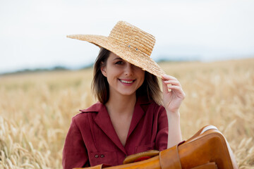 Sticker - young woman with vintage suitcase and hat on a yellow wheat field