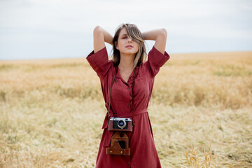 Sticker - young woman in red dress with camera on wheat field