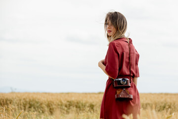 Sticker - young woman in red dress with camera on wheat field