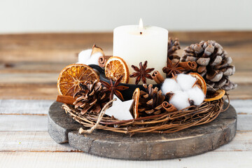 Wall Mural - Rustic decor for christmas holiday family dinner. Center piece with white candle, dry orange, cones, cotton. Zero waste eco friendly home decoration. Cozy atmosphere, wooden background. Close up