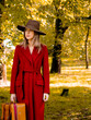 Woman in red coat with suitcase on countryside