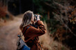 Woman with camera makes a photo in mountain forest