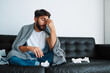 © baranq - Man suffering sinusitis sitting on couch at home having headache
