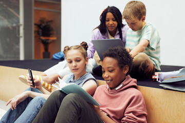 Wall Mural - Portrait of diverse group of children relaxing during break in modern school interior