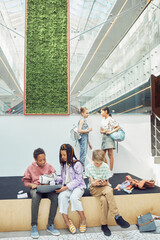 Wall Mural - Vertical wide angle view at diverse group of children at break in modern school interior