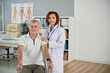 © DragonImages - Smiling physical therapist and senior patient sitting in wheelchair after first rehabilitation session