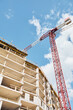 © Seventyfour - Vertical low angle shot of construction crane building residential house against blue sky, copy space
