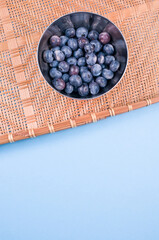 Sticker - Top view of little metal pottery bowl filled with fresh ripe blueberries isolated on blue background