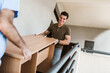 Man Movers Carrying Table On Staircase Of House