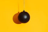 Fototapeta Mapy - Black matte bauble with hard shadow on yellow background