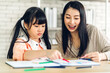 © Art_Photo - Portrait love asian family mother and little asian girl learning and writing in book with pencil making homework at home