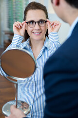 Wall Mural - woman trying on glasses in optical store